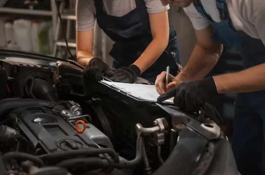 A mechanic verifying vehicle inspection results at the engine bay.